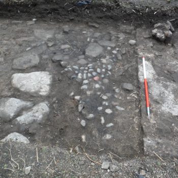 An earlier wall and cobbled floor surface truncated by the later 18th century mansion house wall (scale = 1m).