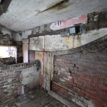 The timber stalls infilled with brick on the southern interior wall of the eastern wing's central northern room. © Copyright ARS Ltd 2021.